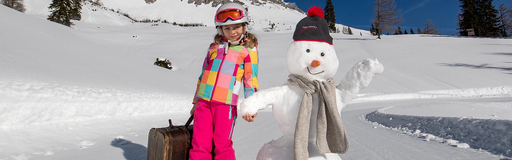 Mädchen steht neben Schneemann in der Winterlandschaft